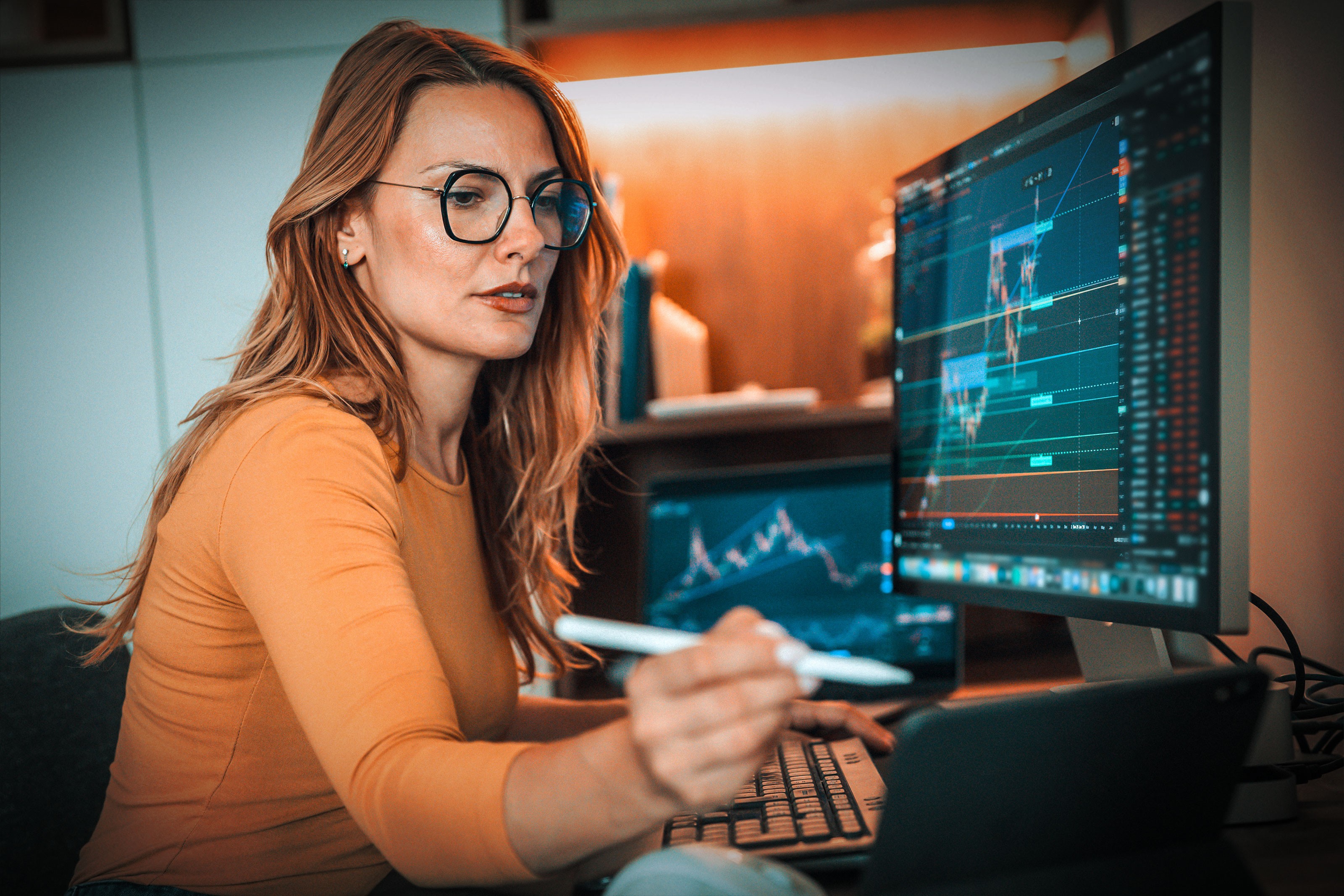 Frau sitzt vor Computer und blickt auf die Kursentwicklungen ihrer Investments